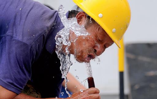 p43-3 8 月1 日，太原市高温来袭，工人在烈日炙烤中作业，用水管冲凉解渴。CFP