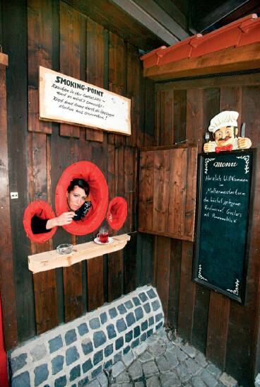 p46-3 2008 年1 月13 日，德国下萨克森州戈斯拉镇，一家餐厅在墙上开洞，并铺上红色软垫，方便烟民“户外”吸烟。当月1 日起，德国在酒吧和餐厅实施禁烟令。