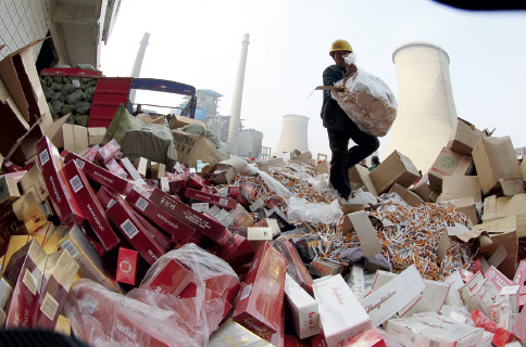 p72 2014 年“3·15”前夕，河南省许昌市，工人将假冒伪劣香烟倾倒在焚烧炉旁，准备用于燃烧发电。CFP
