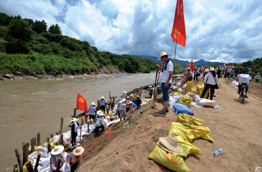 p46(3)7 月3 日，湖北黄冈，罗田县胜利镇金家河岸路基垮塌，党员群众奋力加固堤防。