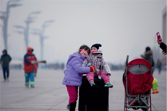 p50 2016年12月11日，北京雾霾再度来袭，在鸟巢附近广场上，一位母亲正在给两个孩子合影。