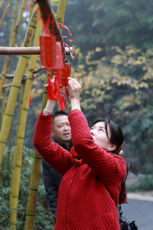 游客将祈福牌挂在竹子上祈愿新年节节高