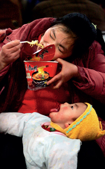 p30 2006 年1 月18 日，西客站候车室，一位母亲为了喂年幼的孩子把方便面咬成一小截，孩子却等不及地张大了嘴巴 。此图为CFP 年度日常新闻类金奖。