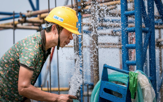 p43(3) 四川德阳，一名工人在高温下用水管冲洗降温。