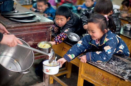 45-2 2013 年2 月28 日，江西鄱阳县鸡峰村小学的老师给学生们发放免费午餐。米饭每人四两（管吃饱）；每餐保证孩子一菜一汤，其中有一份是荤菜；煮鸡蛋一周每人一个。这些孩子们从此告别了中午不吃饭或吃腌菜的生活。<p>图片来源： 视觉中国</p>