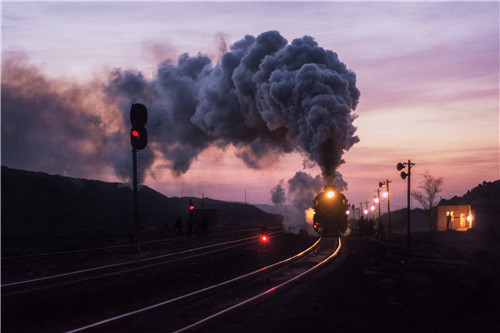 38 2018年1月15日，煤矿矿坑里，蒸汽机车被笼罩在紫色的夕阳下。如今，这些烧煤、冒烟的老家伙已逐渐被内燃机车、电力机车、高速动车组所替代。