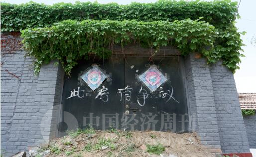 p30-艺术家马万明在辛店村的住宅，门前被村民堆放土堆，门上写着“此房有争议”。《中国经济周刊》记者 胡巍I 摄