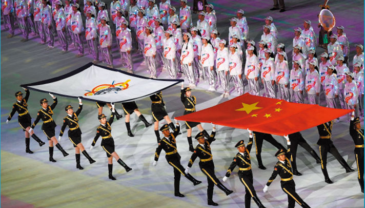 伴随着《歌唱祖国》的嘹亮歌声，16 名仪仗兵分别护拥着中华人民共和国国旗、国际军事体育理事会会旗走进现场。