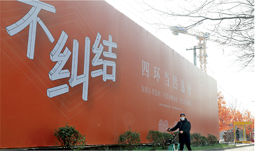 p41-12 月19 日，市民经过北京市丰台区樊羊路一处售楼中心。受新冠肺炎疫情影响，实地看房人数减少，各房企纷纷开启线上 VR 选房模式，部分楼盘启动促销模式。