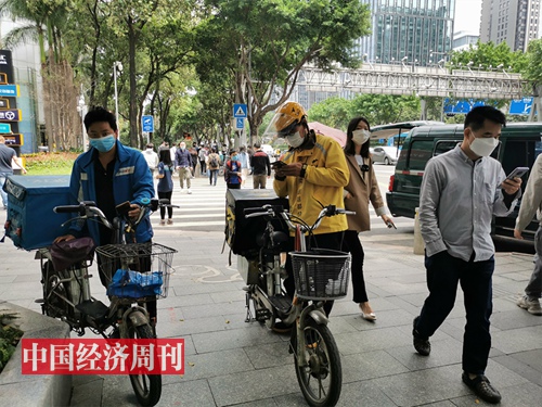 美团和饿了么外卖小哥正在等顾客取餐  摄影：《中国经济周刊》记者 罗赟