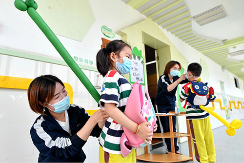 35-1 浙江湖州某幼儿园，教师正在为排队的孩子安装“一米尾巴”，保持安全距离。